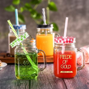 Handmade glass mason jar mugs with colorful lids and straws for drinks.