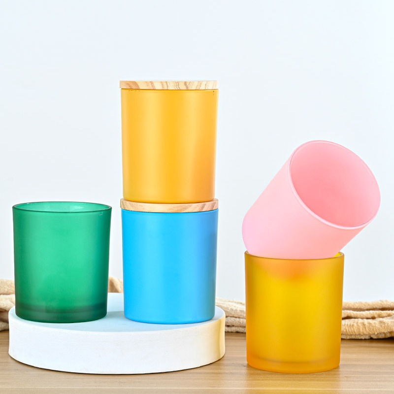 Vibrant handmade glass cups in yellow, green, blue, and pink, perfect for candles or decorative use.